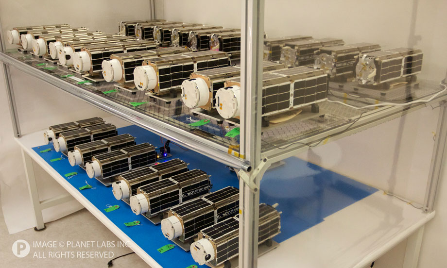 Shelves with dozens of Planet Labs Dove series camera satellites